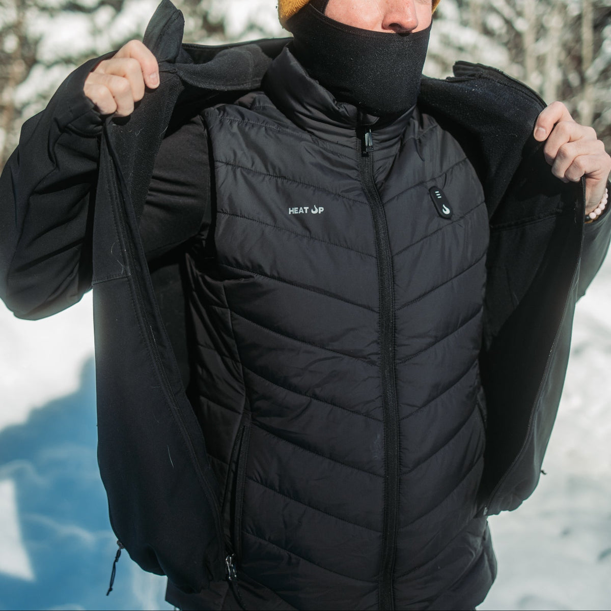 Person opening their jacket in the snow to show the Heat Up heated vest worn underneath