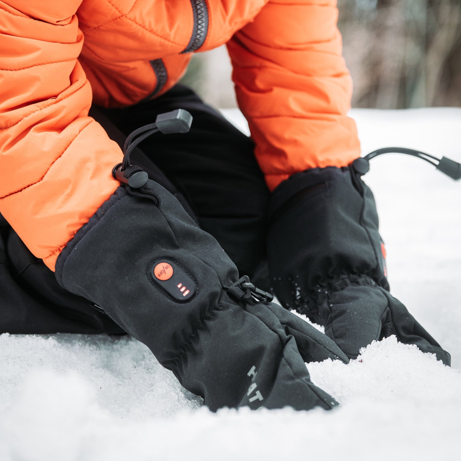 Person wearing heated gloves in a snowy setting