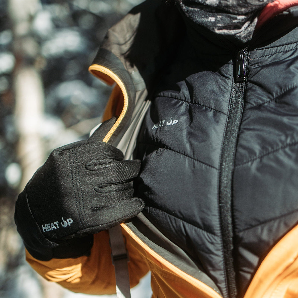 Gloved hand opening an orange jacket to reveal the Heat Up men's heated vest