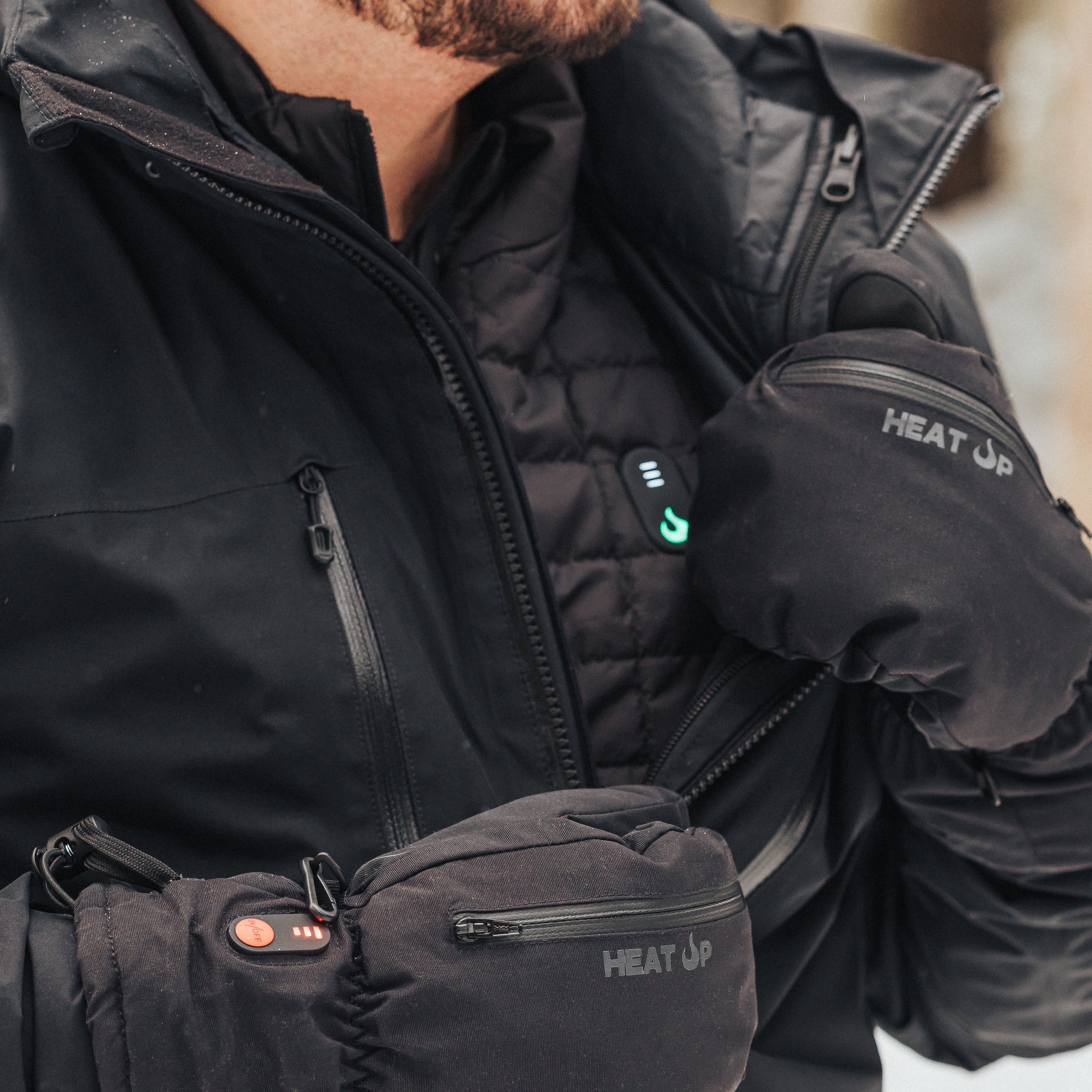 Person wearing a black heated jacket and gloves with 'Heat Up' branding.