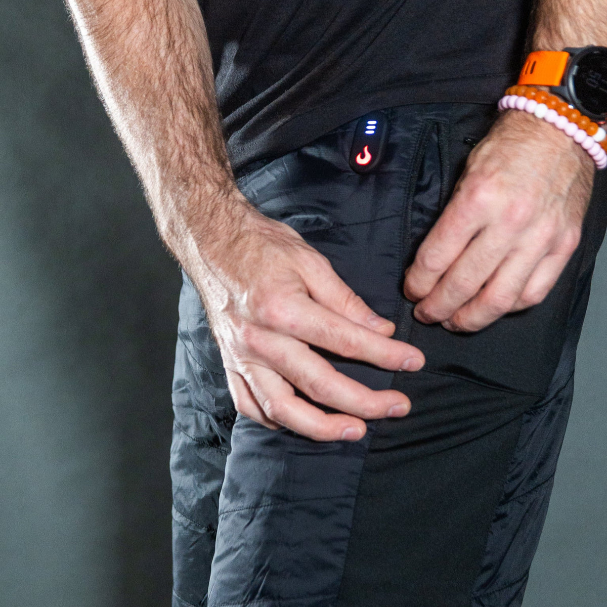 Person wearing and zipping the pocket of the heatup heated shorts mountain series heated shorts