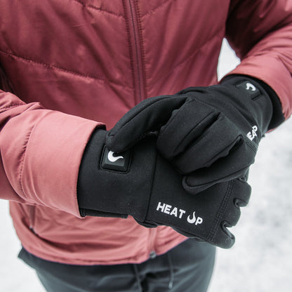 Person wearing black gloves with 'HEAT UP' branding in a snowy setting