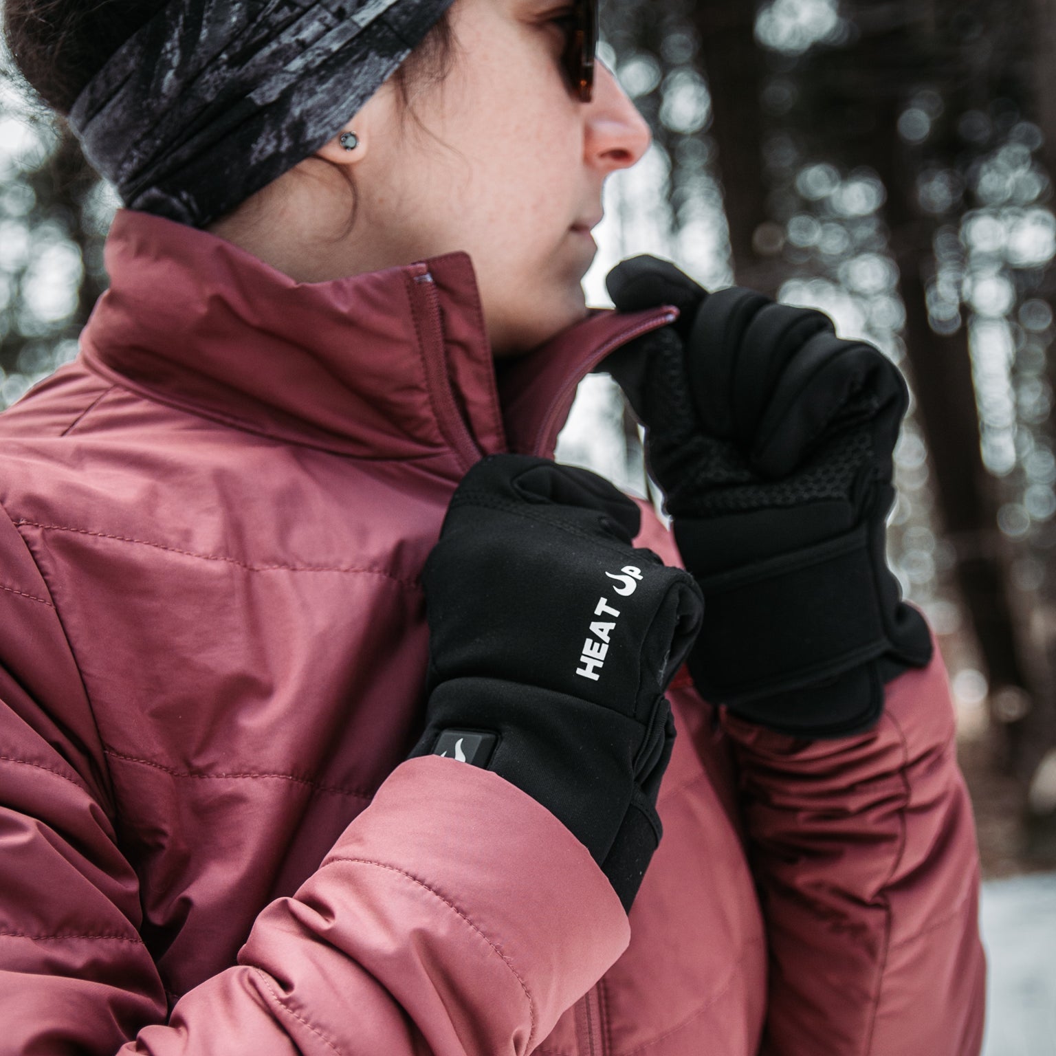 Person wearing a red jacket and black gloves with 'HEAT' branding in a snowy outdoor setting