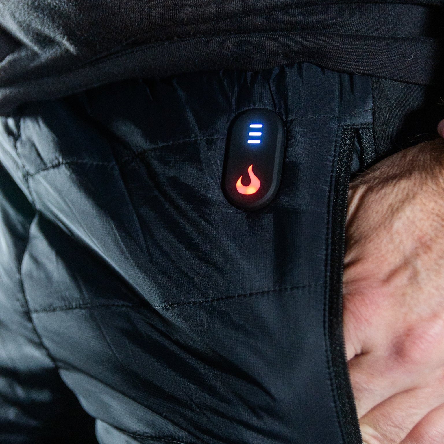 Black heated jacket with a visible heating element on a person wearing it.