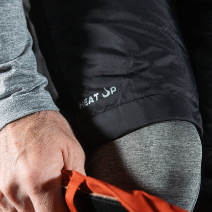 Person wearing a black jacket with 'HEAT UP' branding, holding an orange item.