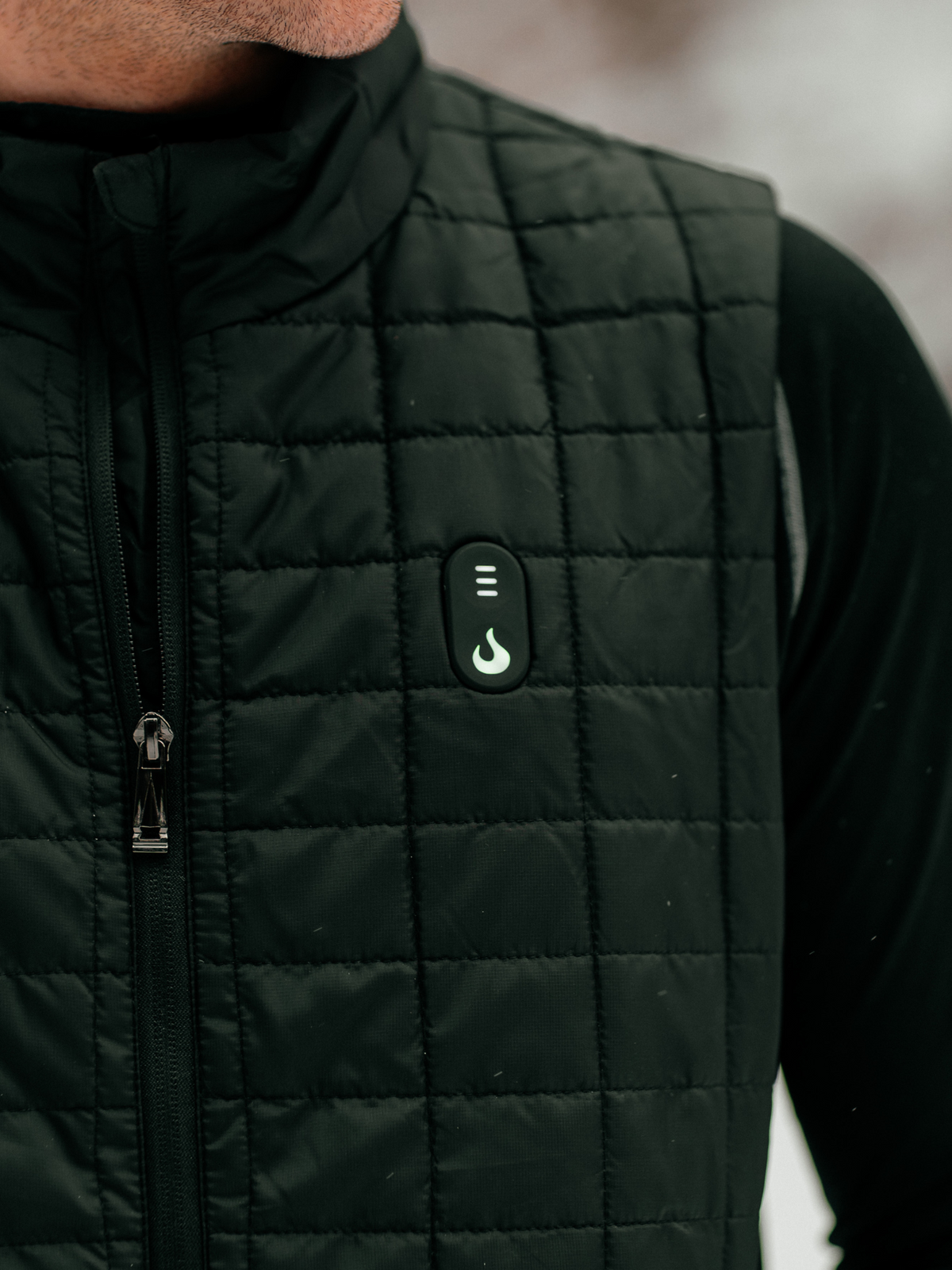 Gros plan sur le bouton de niveau de chaleur et la fermeture éclair de la veste chauffante Heat Up pour homme