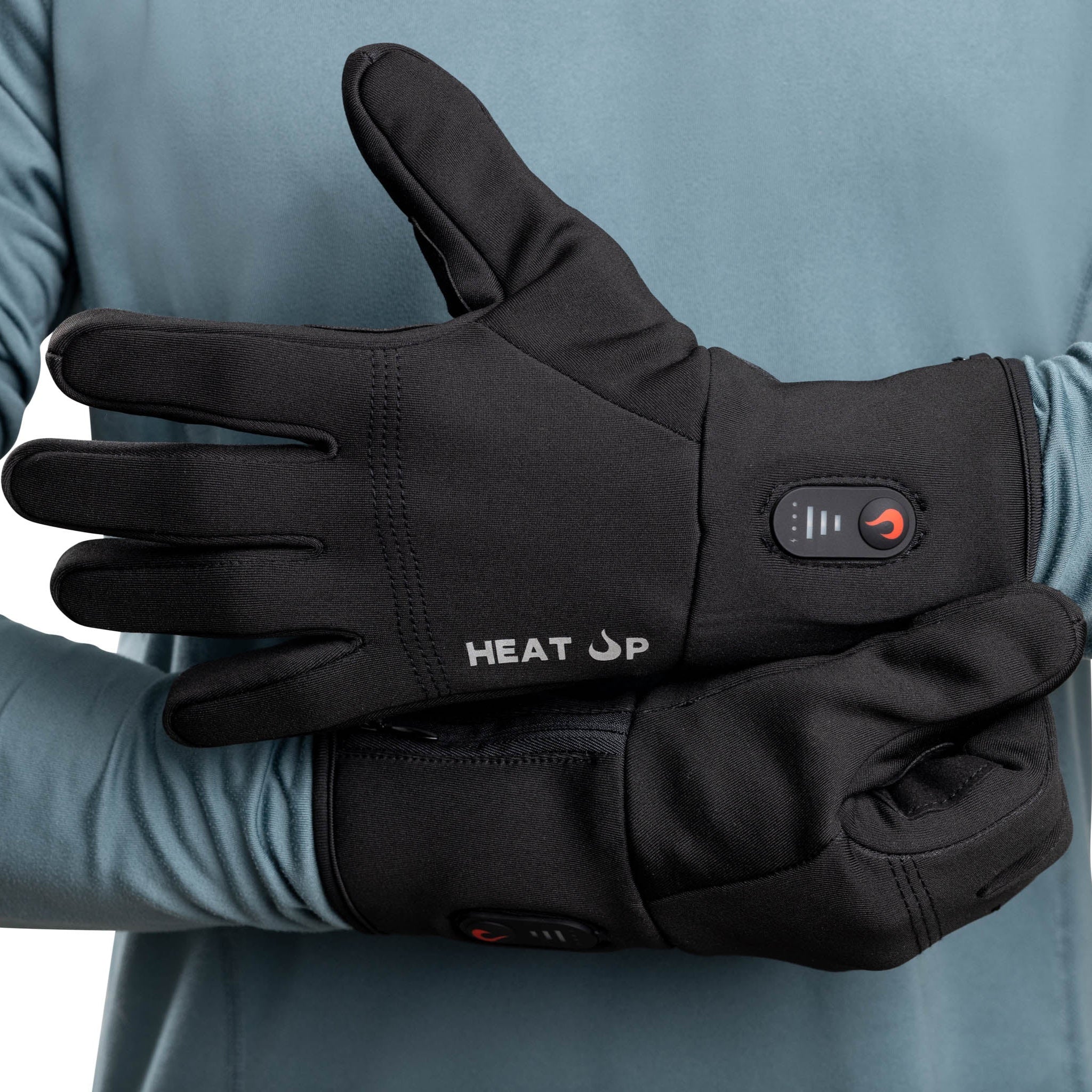 Black heated gloves with 'HEAT UP' branding on a person wearing a blue long-sleeve shirt.