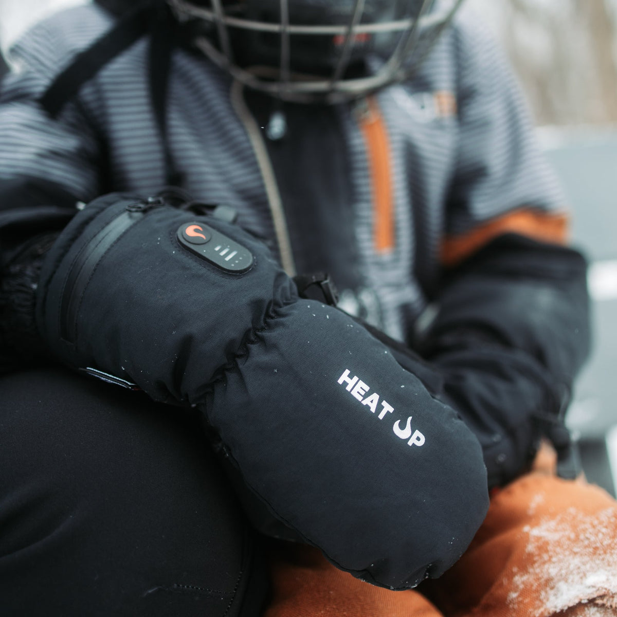Enfant avec un casque de hockey portant des mitaines chauffantes Junior Heat Up, bouton de chaleur allumé