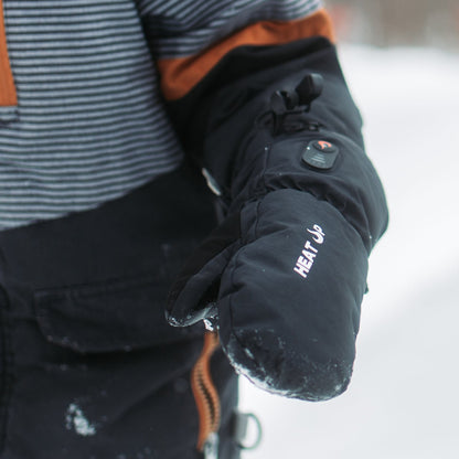 Enfant en habit de neige portant une mitaine chauffante Junior Heat Up, bouton de chaleur allumé
