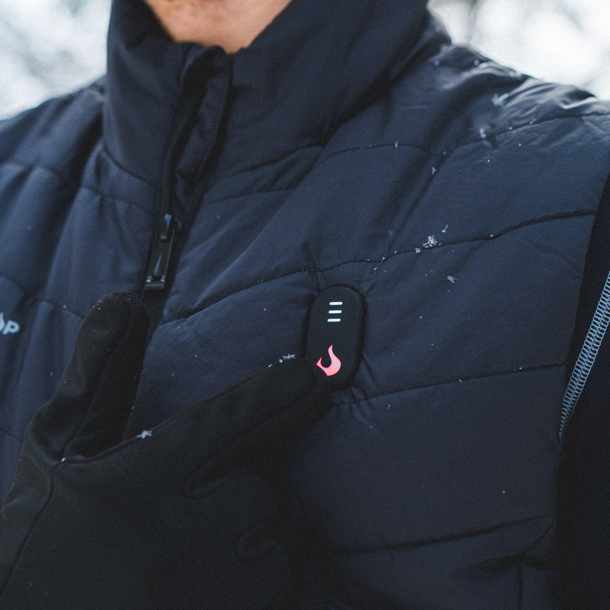 Gros plan sur le bouton de chaleur allumé sur la poitrine de la veste chauffante Heat Up pour homme