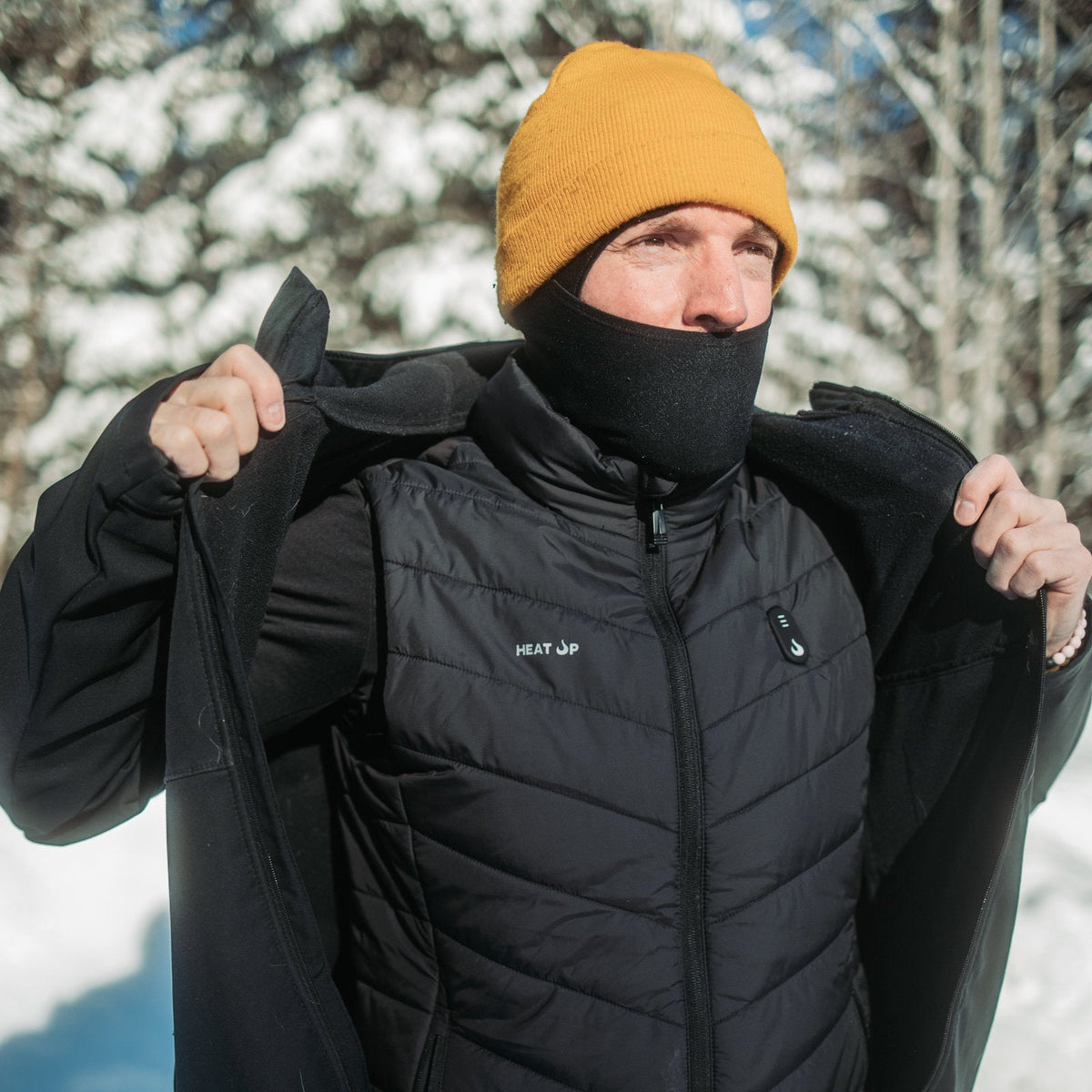 Man in a yellow toque and neck warmer opening his jacket to show the Heat Up men's heated vest