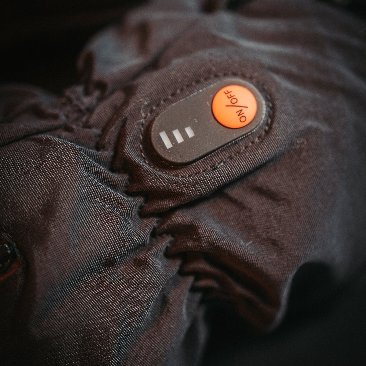 Close-up of the ON/OFF heat button and level indicator on the cuff of a Heat Up Mountain heated glove