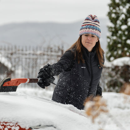 Woman wearing the Heat Up women's heated vest while brushing snow off a car