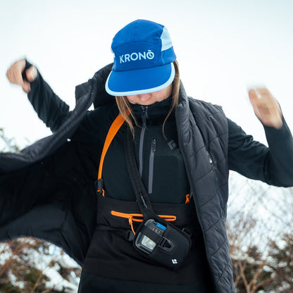 Runner in a cap putting on the Heat Up women's heated vest over a running harness in winter